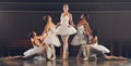 The most essential thing in dance discipline is devotion. a group of ballet dancers practicing a routine on a stage.