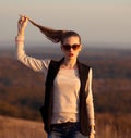 Fashionable,glamorous model stand on hills and held ponytail.Attractive,beautiful girl with sunglasses look at sunset. Royalty Free Stock Photo