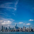 Blue skies fill the picture of the San Francisco skyline and the bay bridge crossing in front of the skyscrapers and water