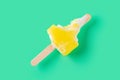 a mostly eaten yellow popsicle on a light green background