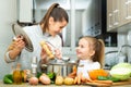 Mother add pepper to vegetable soup and small daughter tasting Royalty Free Stock Photo