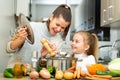 Mother add pepper to vegetable soup and small daughter tasting Royalty Free Stock Photo