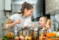 Mother add pepper to vegetable soup and small daughter tasting Royalty Free Stock Photo