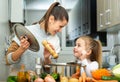 Mother add pepper to vegetable soup and small daughter tasting Royalty Free Stock Photo