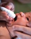 Mother administrating liquid medicine in drops to her baby