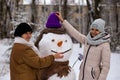 Mother and adult daughter sculpt a big real snowman Royalty Free Stock Photo