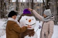 Mother and adult daughter sculpt a big real snowman Royalty Free Stock Photo