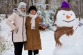 Mother and adult daughter sculpt a big real snowman Royalty Free Stock Photo