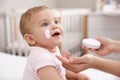 Mother applying moisturizing cream on her little baby at home, closeup Royalty Free Stock Photo