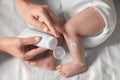 Mother applying moisturizing cream onto baby`s leg on bed, top view Royalty Free Stock Photo