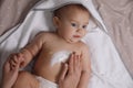 Mother applying moisturizing cream onto her little baby`s skin on bed Royalty Free Stock Photo