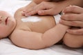 Mother applying moisturizing cream onto her little baby`s skin on bed, closeup Royalty Free Stock Photo