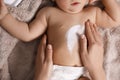 Mother applying moisturizing cream onto her little baby`s skin on towel, closeup Royalty Free Stock Photo