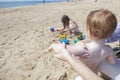 Mother applying sun cream to her baby while her daughter play on Royalty Free Stock Photo