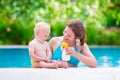 Mother applying sun screen on baby in swimming pool Royalty Free Stock Photo