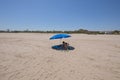 Mother applying sunscreen on child under umbrella at beach Royalty Free Stock Photo