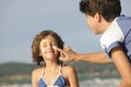 Mother applying sunscreen to daughter at beach.