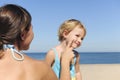 Mother applying suntan lotion to her daughter