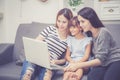 Mother, Aunt and kid having time together lerning with using laptop computer at home with relax and happy on couch