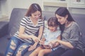 Mother, Aunt and kid having time together lerning with using tablet at home with relax and happy on couch