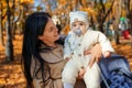 mother and baby are in autumn city park, happy people walking together, family with children, playing with yellow leaves, Royalty Free Stock Photo