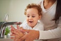 Mother, baby and bathroom cleaning their hands for health and hygiene in home. Child, water and mom teaching to wash Royalty Free Stock Photo