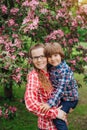 Mother and baby in blooming garden. Mom and child in spring. Springtime family scene. Flowers of apple or cherry tree