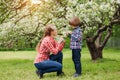 Mother and baby in blooming garden. Mom and child in spring. Springtime family scene. Flowers of apple or cherry tree