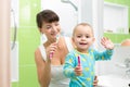 Mother with baby brushing teeth in bathroom