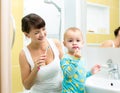 Mother and baby brushing teeth in bathroom Royalty Free Stock Photo