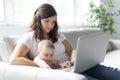 Mother and baby child are looking to play and read computer on the couch at home Royalty Free Stock Photo