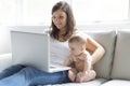 Mother and baby child are looking to play and read computer on the couch at home Royalty Free Stock Photo