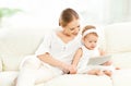 Mother and baby child with tablet computer on the couch at home Royalty Free Stock Photo