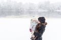 Mother with baby daughter in hands standing near the snow-covered pond Royalty Free Stock Photo