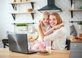 Mother with baby daughter sitting at table with groceries in kitchen with laptop Royalty Free Stock Photo