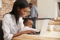 Mother And Baby Daughter Use Laptop As Father Prepares Meal Royalty Free Stock Photo