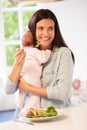Mother With Baby Eating Healthy Meal In Kitchen Royalty Free Stock Photo