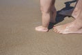 Mother and baby feet walking on sand beach