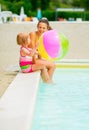 Mother and baby girl with beach ball at poolside