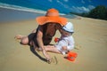 Mother with baby girl drawing on sandy beach Royalty Free Stock Photo