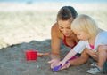 Mother and baby girl playing with sand on beach Royalty Free Stock Photo