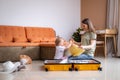 Mother and baby girl with yellow suitcase baggage and clothes, family ready for traveling on vacation at home Royalty Free Stock Photo