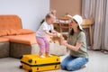 Mother and baby girl with yellow suitcase baggage and clothes, family ready for traveling on vacation at home Royalty Free Stock Photo