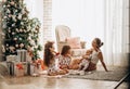 Mother with a baby on her hands sits o the carpet with her two daughters dressed in pajamas eating cookies with cocoa Royalty Free Stock Photo