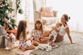 Mother with a baby on her hands sits o the carpet with her two daughters dressed in pajamas eating cookies with cocoa Royalty Free Stock Photo