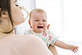 Mother and baby hugging and consoling at bedroom