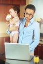 Mother, baby and laptop for work from home, online planning and business research or multitasking in kitchen. Single mom Royalty Free Stock Photo