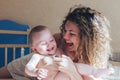 Mother and baby laughing on bed