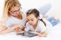 Mother and baby are looking to play and read tablet computer on the couch at home Royalty Free Stock Photo