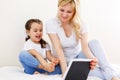 Mother and baby are looking to play and read tablet computer on the couch at home Royalty Free Stock Photo